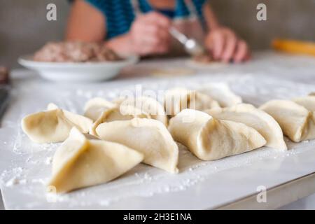 Sul tavolo giacciono i manti grezzi triangolari. Preparazione della cottura Foto Stock