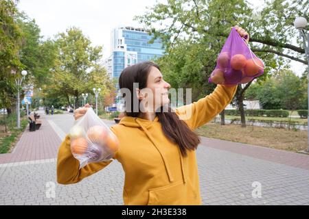 La donna conserva verdure e frutta in un sacchetto di plastica e un acquirente di stoffa. Foto Stock