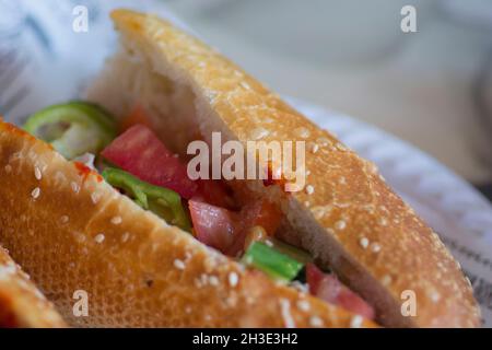 Primo piano di un panino tunisino, contenente solitamente tonno impaccato, uova sode, patate, olive o sottaceti, limone conservato, e pasta di harissa Foto Stock