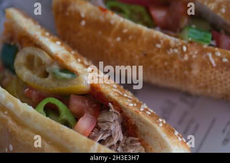 Primo piano di un panino tunisino, contenente solitamente tonno impaccato, uova sode, patate, olive o sottaceti, limone conservato, e pasta di harissa Foto Stock