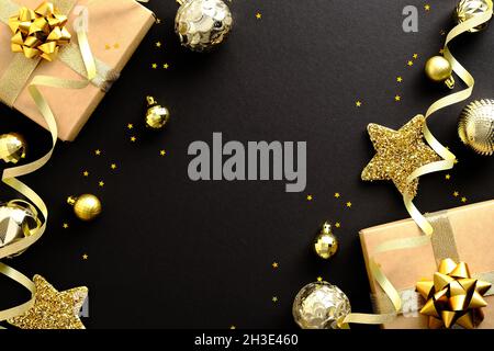 Elegante composizione Christmas Flat Lay. Decorazioni dorate, palle, stelle, regali, confetti su sfondo nero. Cornice di Natale, banner design, Natale gr Foto Stock