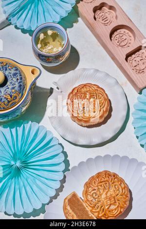 Dall'alto delle tradizionali mooncake con ripieno servito sul tavolo con stampi da forno vicino bollitore con tè alle erbe in camera luminosa Foto Stock