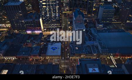 Bella vista ad angolo del centro di Calgary, Canada, con edifici illuminati in serata e auto di guida per le strade. Foto Stock