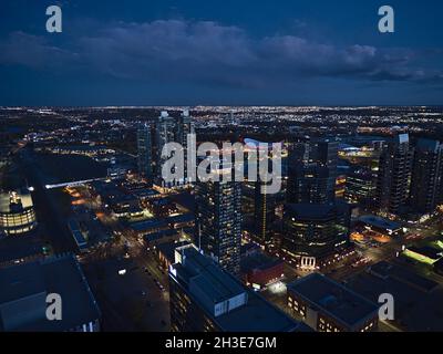 Splendida vista ad alto angolo del centro di Calgary sud-orientale con edifici illuminati e alti e Stampede con arena coperta Scotiabank Saddledome. Foto Stock