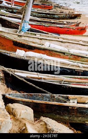 Fila di barche di legno invecchiate ormeggiate sulla spiaggia di sabbia dell'oceano su São Tomé e Príncipe isola in giorno di sole Foto Stock
