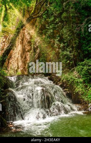 Vista laterale della cascata sotto gli alberi in una giornata di sole Foto Stock