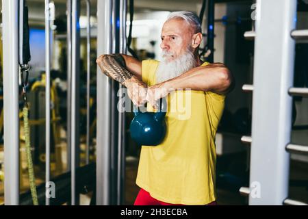 Hipster senior man training all'interno della palestra - concentrarsi sulle mani che tengono kettlebell Foto Stock