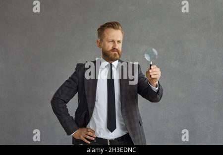 Foto ritratto studio di un uomo d'affari concentrato in abito con lente di ingrandimento Foto Stock