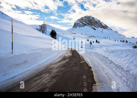 Strada deserta passo di montagna sgombrata di neve in una giornata invernale poco nuvolosa Foto Stock