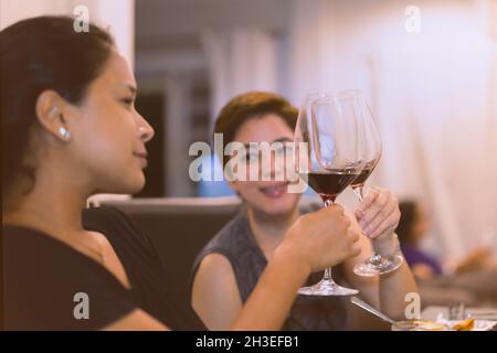 Un amico che tostava con bicchieri di vino rosso a cena. Foto Stock