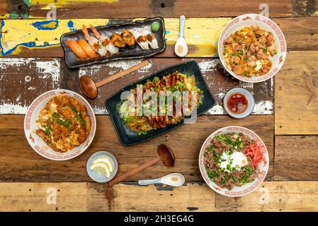 Set di piatti asiatici e condimenti, tagliatelle, salsa di soia, sesamo, ramen, sushi di nigiri, cucchiai, limone, wasabi, maiale e pollo Foto Stock