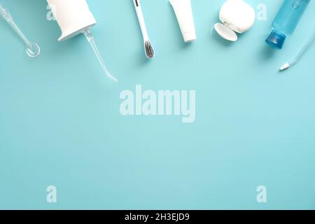 Irrigatore orale dentistico professionale, dentifricio, spazzolino da denti, liquido, flosser su sfondo blu. Disposizione piatta, vista dall'alto. Sovratesta. Banner medico dentale des Foto Stock