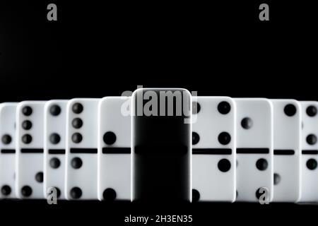Pezzi Domino messi in fila su sfondo nero Foto Stock