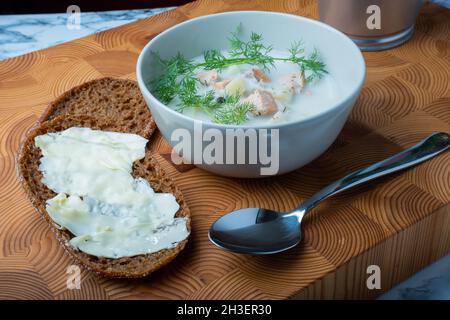 Helsinki / Finlandia - 28 OTTOBRE 2021: Cucina tradizionale finlandese: Ciotola di cremosa zuppa di salmone con aggiunta di aneto. Due pezzi di pane di segale sul lato. Foto Stock