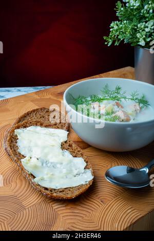 Helsinki / Finlandia - 28 OTTOBRE 2021: Cucina tradizionale finlandese: Ciotola di cremosa zuppa di salmone con aggiunta di aneto. Due pezzi di pane di segale sul lato. Foto Stock