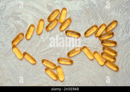 Omega3 capsule in forma di pesce silhouette su sfondo cementizio. EPA e DHA sono sostanze grasse essenziali di cui il nostro corpo ha bisogno quotidianamente. Foto Stock