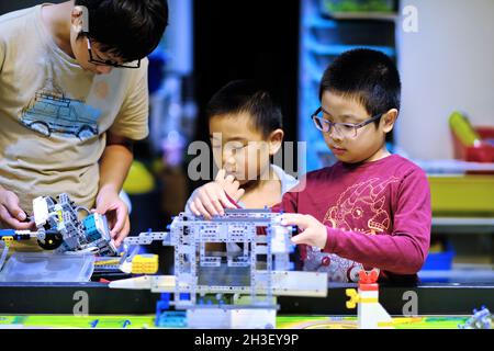 Gruppo di bambini che frequentano la classe di robotica Lego e che costruiscono e testano il robot model.Children ISTRUZIONE STEM ed esperimenti scientifici creativi divertimento. Foto Stock