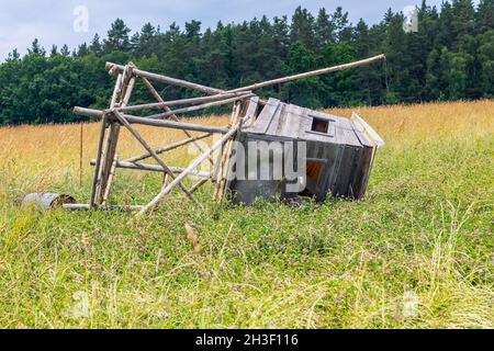 La tenda da caccia è caduta a terra, una struttura in legno di una tenda da caccia che giace in un campo Foto Stock