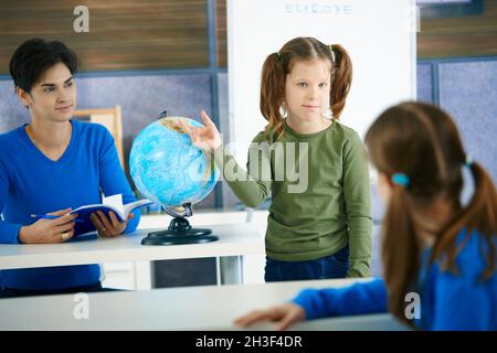 Studentessa che punta al globo Foto Stock