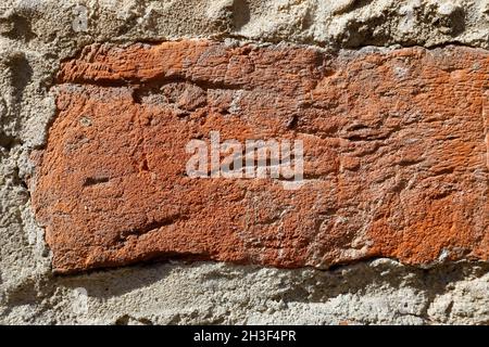 Un frammento della vecchia parete fatta di mattoni rossi Uniti con mortaio. Attualmente, l'intonaco è completamente caduto da questa parete. Foto Stock