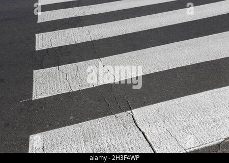 Strisce bianche su asfalto nero è un passaggio pedonale. Foto Stock