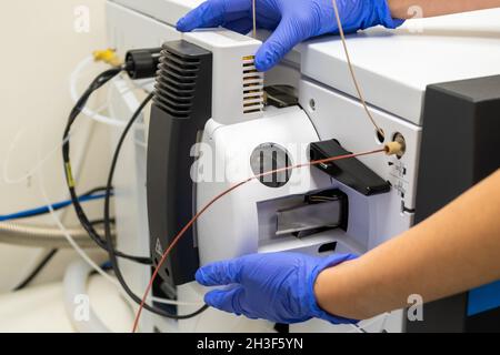 Chemist che apre la sorgente ionica dello spettrometro di massa per la pulizia. Cromatografia liquida con rilevamento di massa per analisi chimiche e microbiologiche Foto Stock