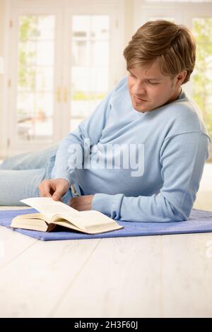 Giovane uomo che legge a casa Foto Stock