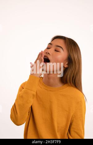 Giovane attraente ragazza assonnata asiatica in studio Foto Stock