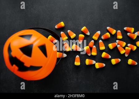 Halloween sfondo. Caramelle di mais caramelle, cestino di zucca. Dolci tradizionali. Spazio di copia. Foto Stock