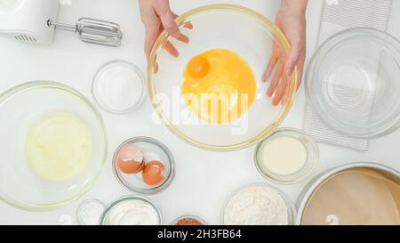 Tuorli d'uovo, albumi, farina, zucchero e alcuni ingredienti per la ricetta della torta da vicino sul tavolo da cucina. Torta di cioccolato fatta in casa passo dopo passo che si cotta la proce Foto Stock