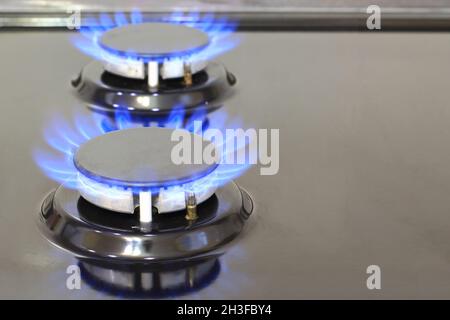 Fornello a gas con fiamme di metano o gas propano. Cucina moderna cucina cottura con fiamme blu che brucia. Risorse industriali e concetto di economia Foto Stock