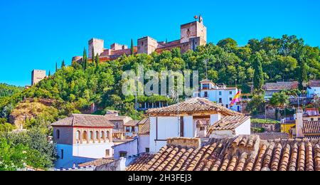 Spettacolare fortezza in pietra dell'Alhambra con mura e torri conservate, vista attraverso il verde della collina Sabika, Granada, Spagna Foto Stock