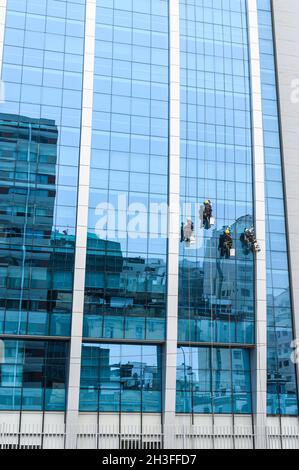 gruppo di lavoratori che puliscono le finestre in un alto edificio Foto Stock