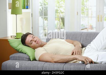 Uomo che dorme sul divano Foto Stock