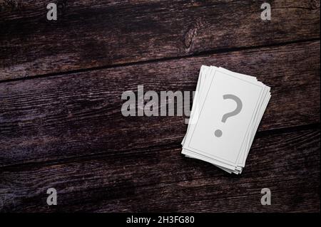 Carte Chance, gioco d'azzardo, FAQ o domande senza risposta concetto. Una pila di carte da gioco, stampate con un punto interrogativo, su un rustico sfondo di legno. Foto Stock