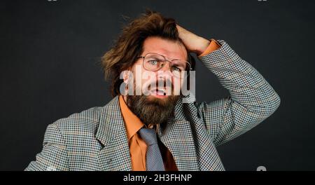 Confuso insegnante di sesso maschile in occhiali. Uomo d'affari bearded nell'abito. Concetto di scuola, istruzione e business Foto Stock