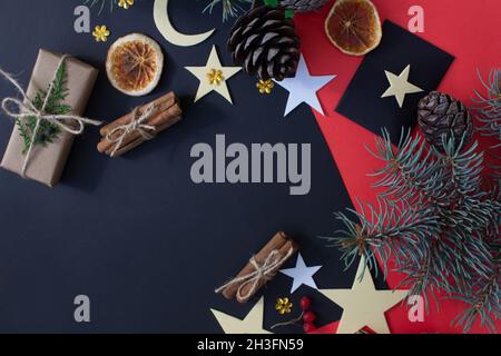 Composizione di Natale su sfondo rosso-nero.regali di Natale, coni di pino, decorazioni di Natale. Foto Stock