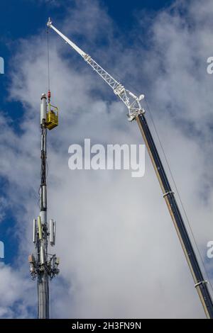 Due tecnici lavorano da un paniere sospeso per completare gli aggiornamenti della torre del cellulare durante le contrattazioni del Congresso sulla spesa per le infrastrutture. Foto Stock