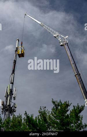 Durante i colloqui infrastrutturali al Congresso, i tecnici lavorano in alto da un man basket per aggiornare le capacità dell'antenna del telefono cellulare. Foto Stock