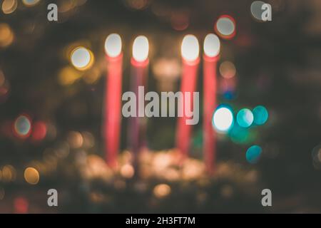 la corona sfocata dell'avvento con candele che bruciano con luci sullo sfondo Foto Stock