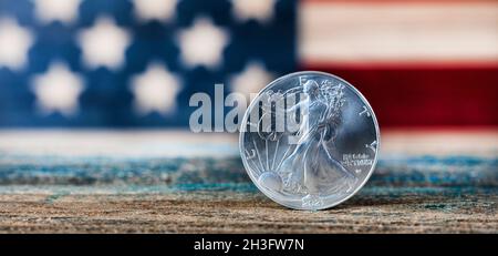 Primo piano di una moneta americana in dollari d'argento con bandiera statunitense sullo sfondo Foto Stock