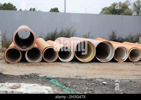 Tubi del carburante. Grandi tubi giacciono vicino alla recinzione. Preparazione della tubazione dell'olio. Anelli industriali. Foto Stock