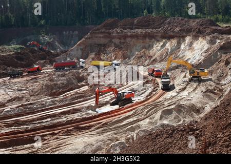Concetto industriale. Bulldozer e una coda di camion in cava di sabbia Foto Stock