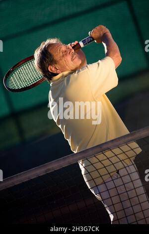 L'uomo anziano gioca a tennis Foto Stock