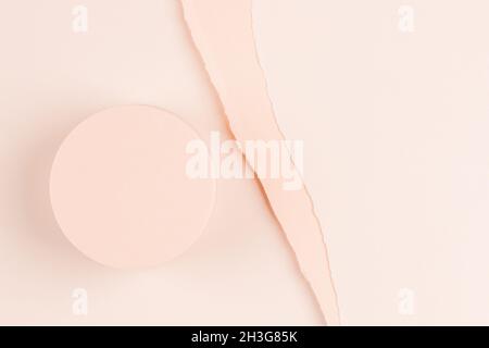 Podio vuoto rotondo beige pastello per la presentazione del prodotto cosmetico su sfondo cartaceo strappato. Vista dall'alto Foto Stock