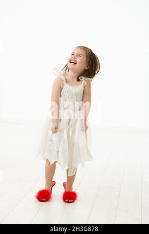 Bambina che cerca scarpe mamme Foto Stock