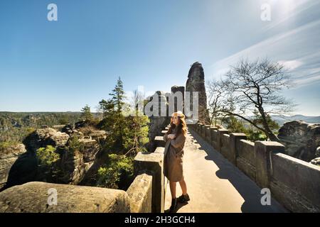 Una ragazza in un cappotto e cappello grigio su un ponte in Sassonia Svizzera, Germania, Bastei Foto Stock