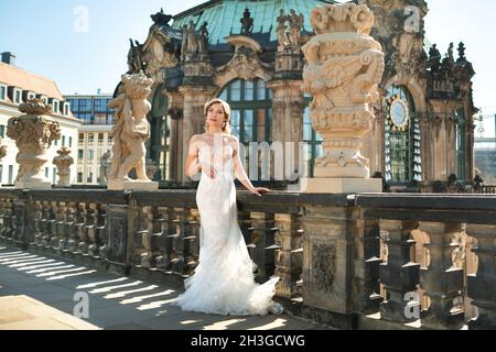 Una sposa in un abito bianco in una passeggiata nuziale presso il famoso Palazzo Barocco Zwinger a Dresda, Sassonia, Germania. Foto Stock