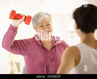 Donna anziana che fa esercizio dumbbell Foto Stock