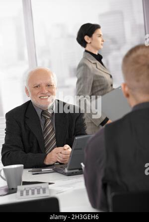 Uomo d'affari anziano sorridente al lavoro Foto Stock